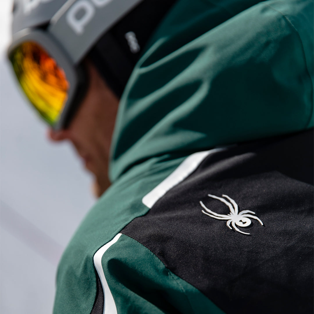rear shoulder of a green and black Spyder jacket with Spyder logo in white