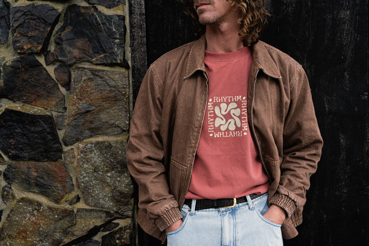 a man in a garden holding up a surfboard in front of him