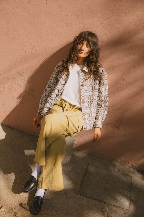 a woman on a beach wearing a white crochet bikini with pink and yellow embroidery