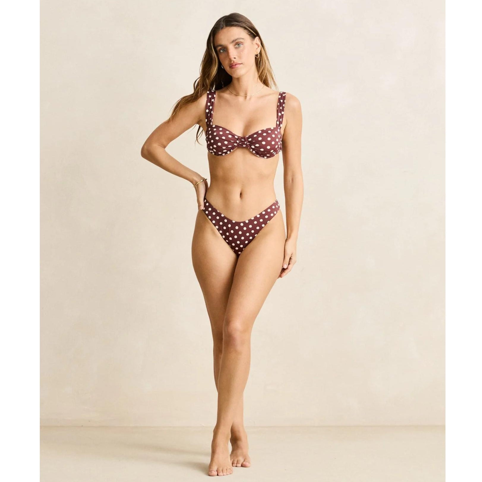 Woman wearing a polka dot bikini against a neutral background