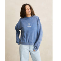 Person wearing a blue sweatshirt with a logo on a beige background